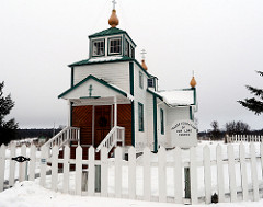 Front entry, Holy Transfiguration of Our Lord Church, graveyard, Russian crosses, American flag, snow, Ninilchik Village, Kenai Peninsula Borough, Alaska, USA